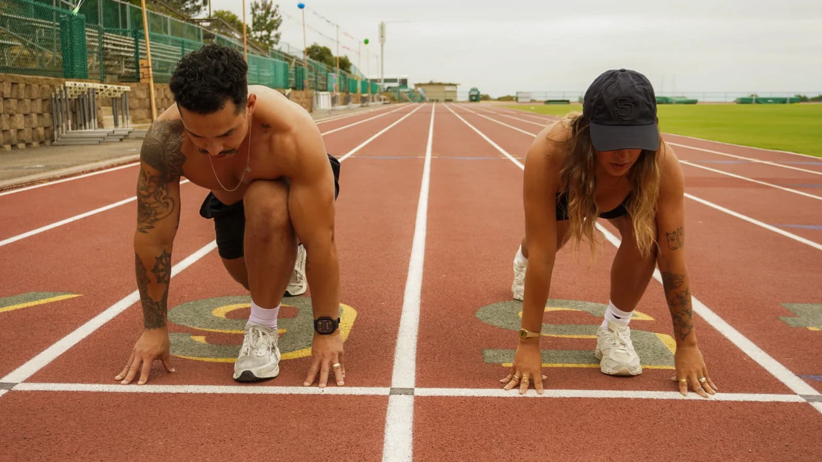 Two athletes in starting positions on a running track.